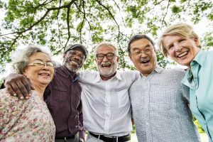 A diverse small group of adults aged 50 or older lean in together and smile