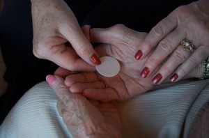 A more youthful hand places a Communion host in a more elderly hand